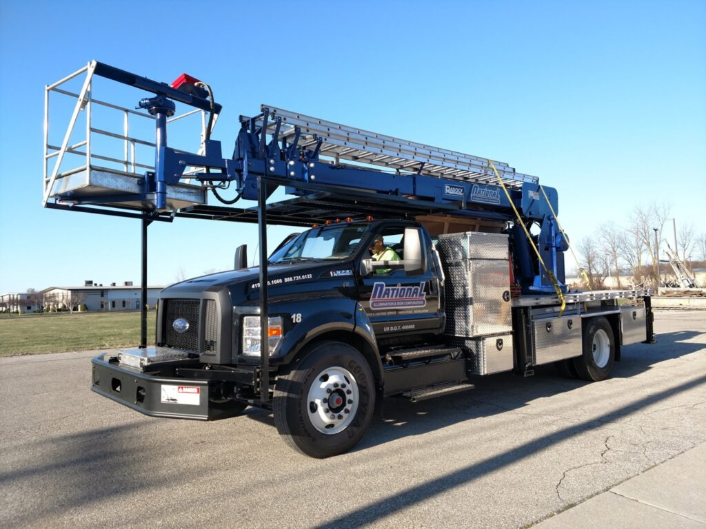 National Illumination & Sign Corporation bucket truck with an extended aerial work platform, ready for a sign service call